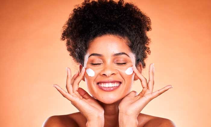 Foto fundo laranja com mulher passando protetor solar