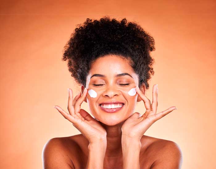 Foto fundo laranja com mulher passando protetor solar